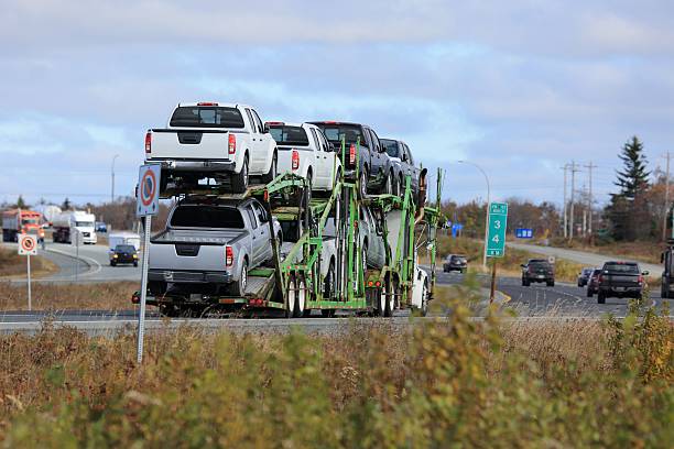 Semi truck car carrier on a highway carrying trucks . Vehicle traffic in the background.